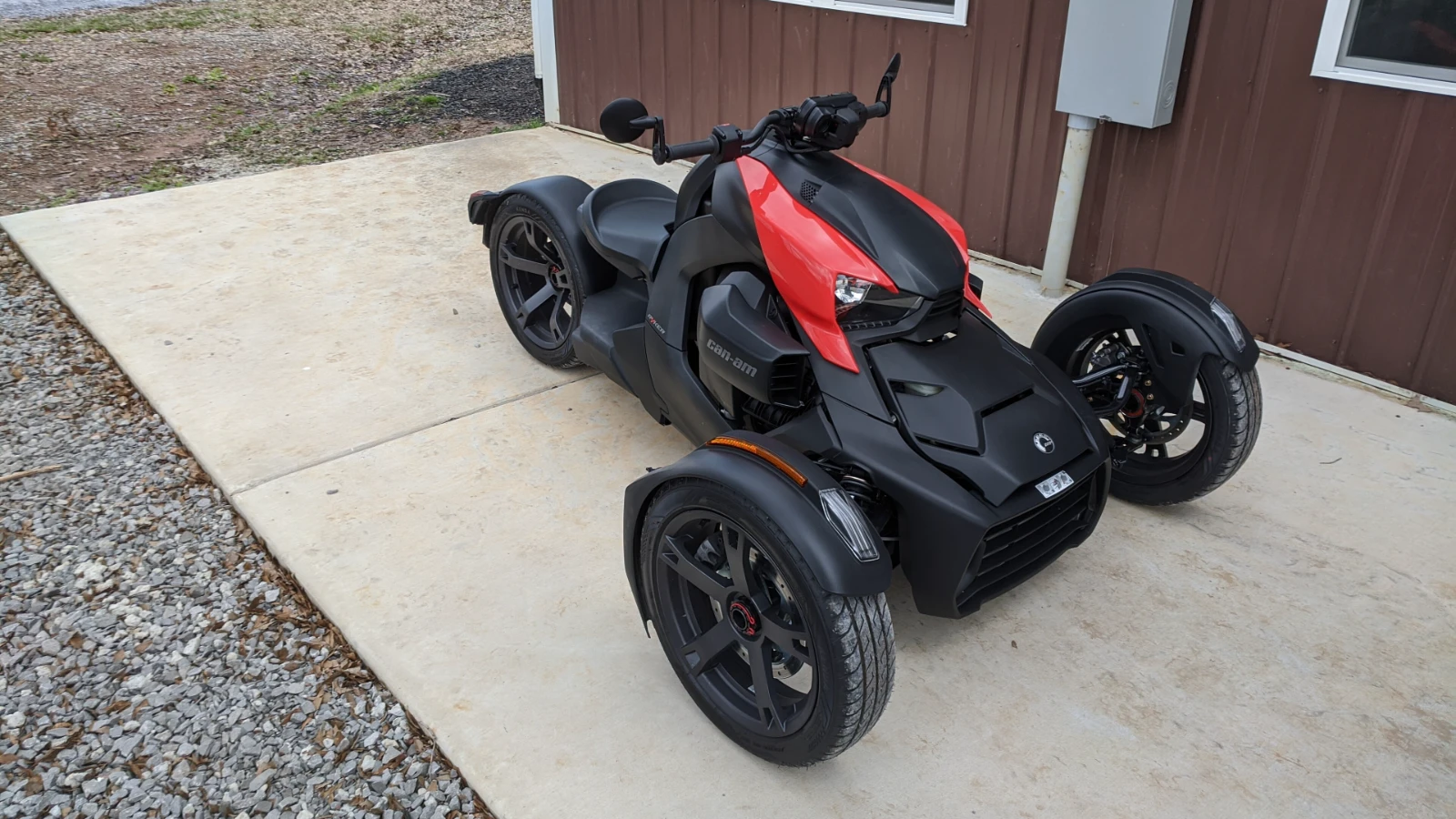 Can-Am Ryker 600 von 2019 in Mattschwarz mit roten Seitenteilen, Dreiviertelansicht von vorn rechts auf einer Betonfläche vor einem Gebäude
